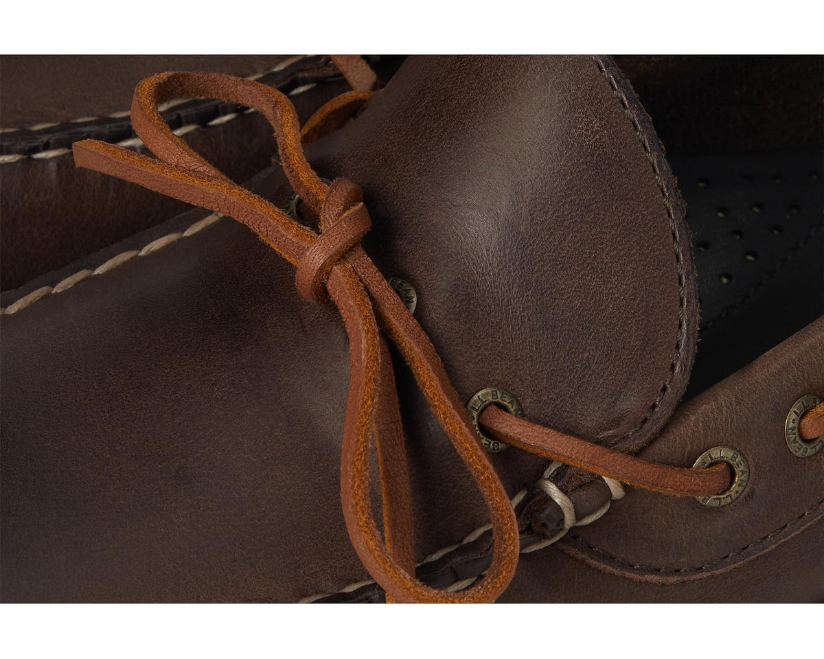 Close-up of dark leather boat shoe laces, eyelets, and stitched moccasin seam
