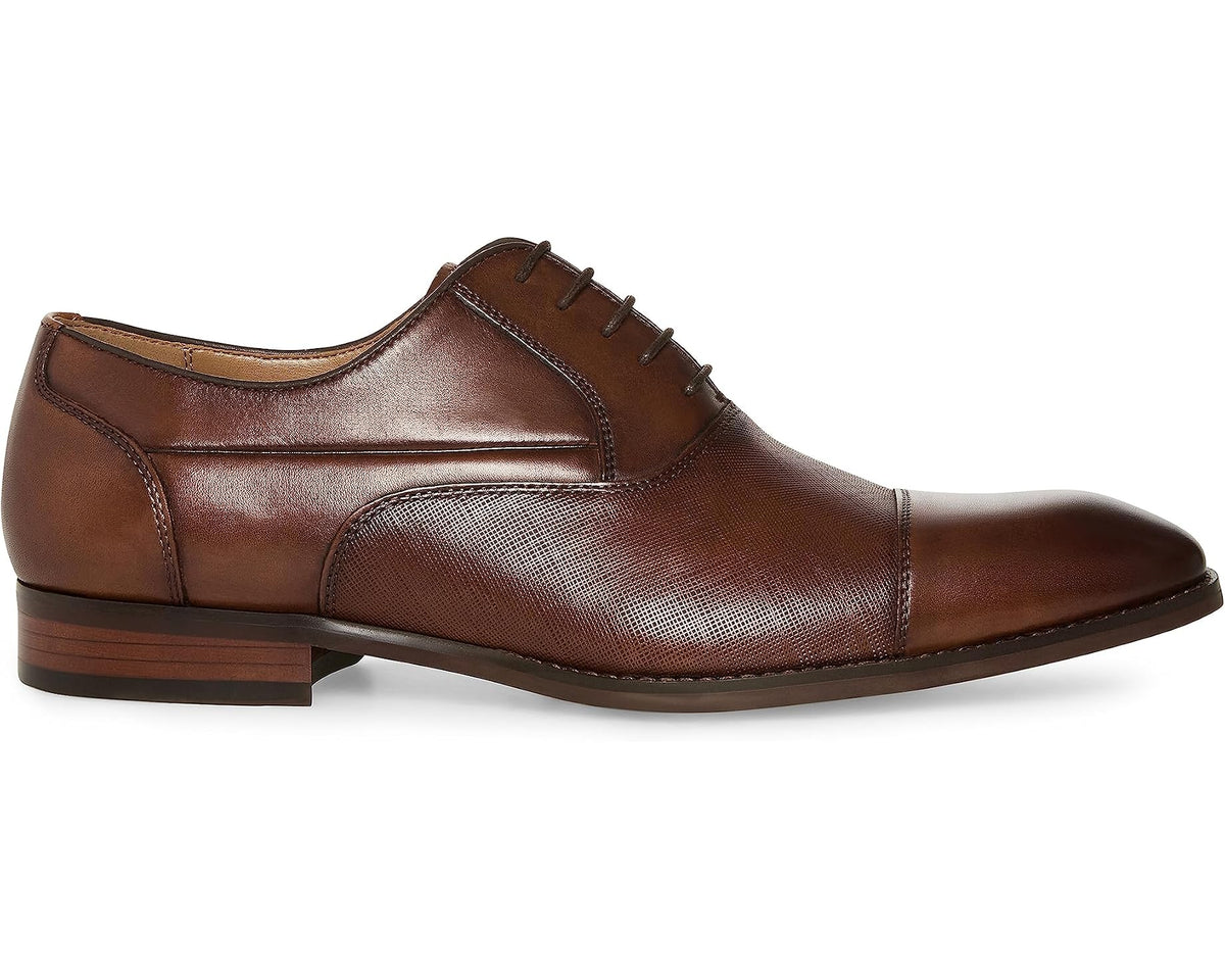 Tan leather lace-up Oxford dress shoe with stitched panels and low heel.