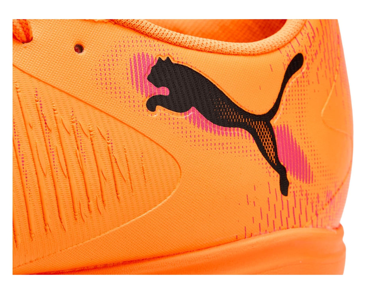 Orange PUMA cleat close-up with black cat logo on textured mesh upper