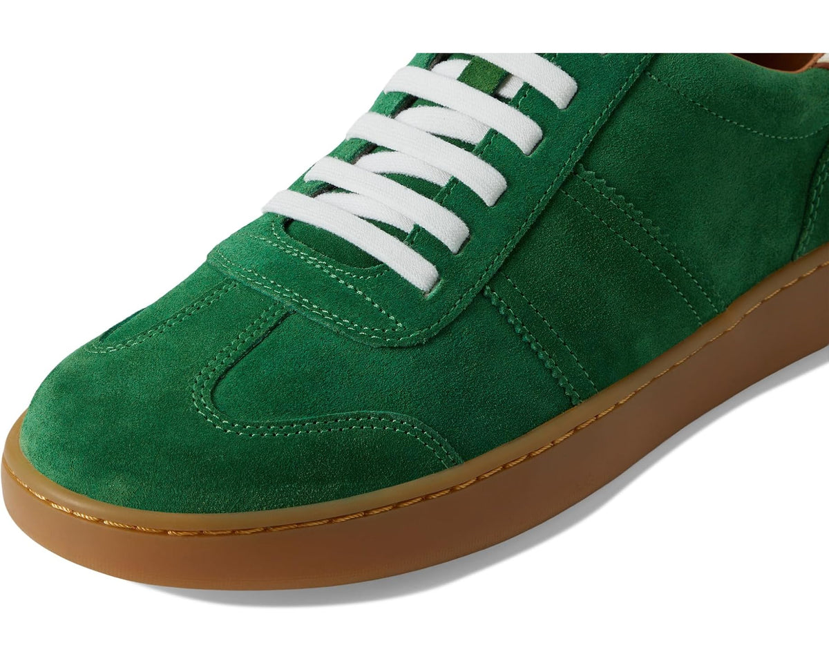 Green suede sneaker with white lace-up, visible stitching, and tan edge sole.