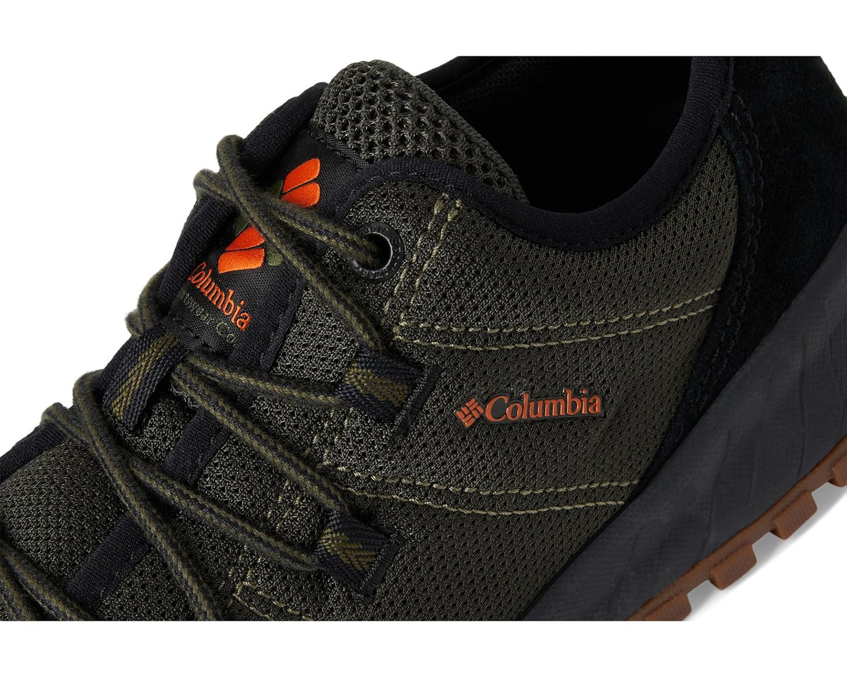 Men's hiking shoe close-up: olive mesh, orange tongue logo, brown outsole edge