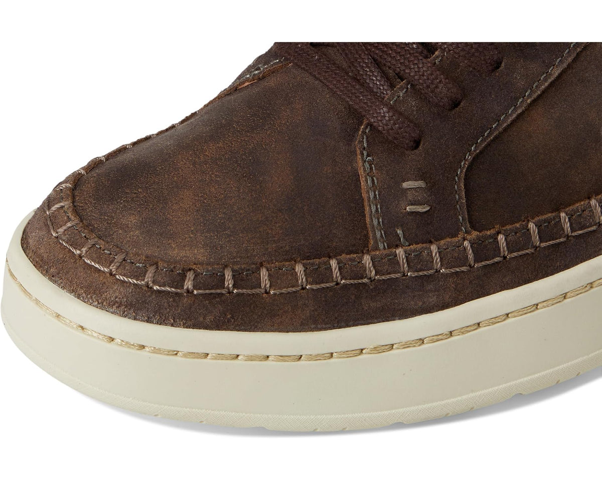 Men's dark brown suede sneaker upper close-up with stitching and lace eyelets