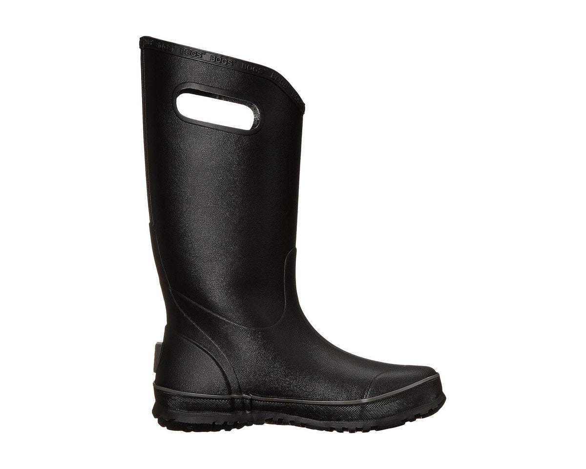 Black rain boot angled side view with oval cutout handle and tread sole