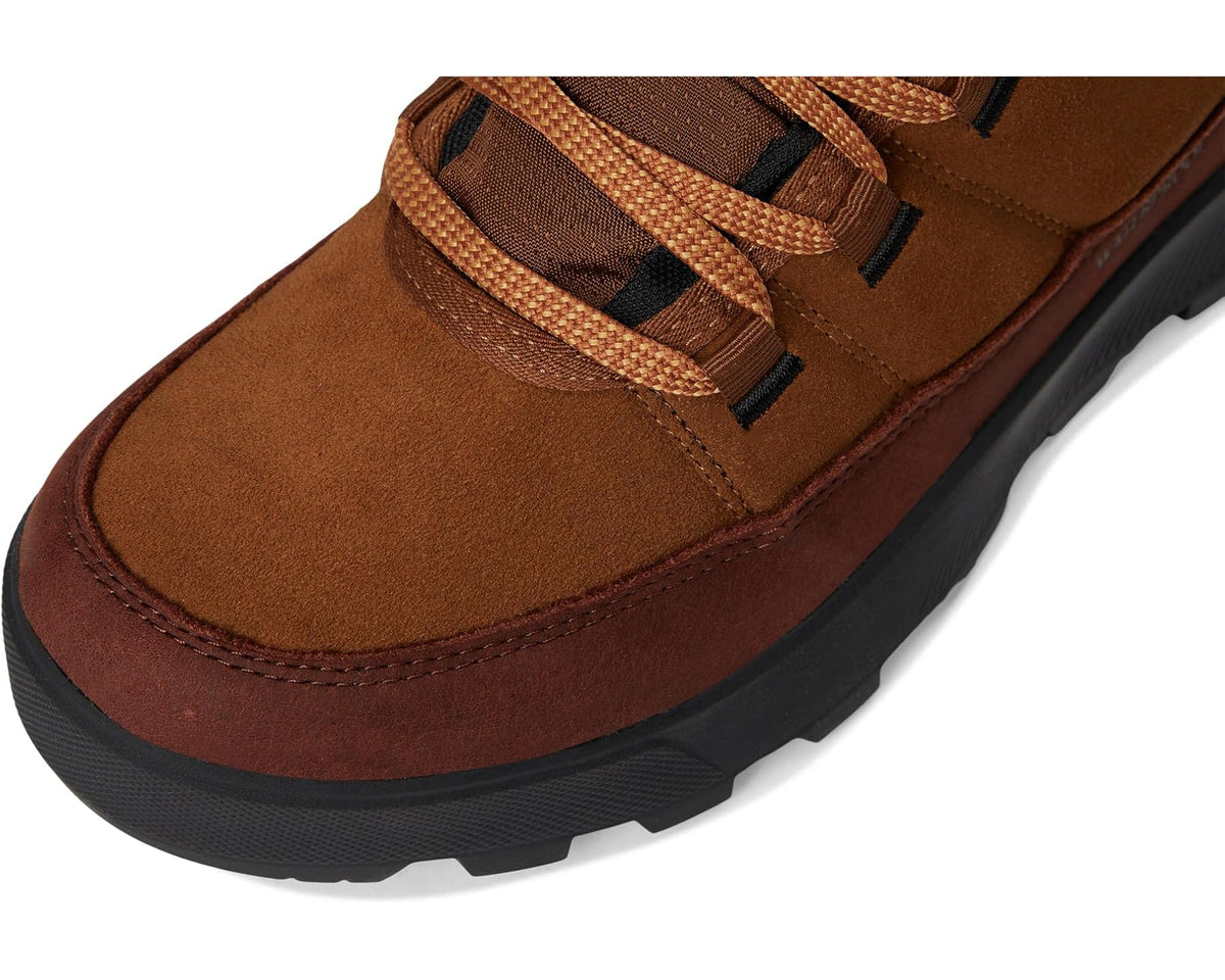 Brown suede boot close-up with laced top, stitched toe, and black rubber sole edge
