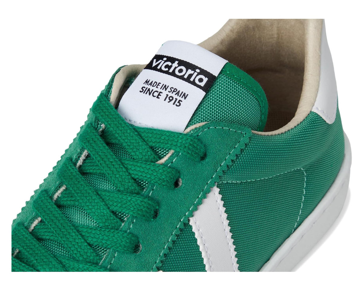 Green lace-up sneaker close-up with victoria tongue label and beige lining