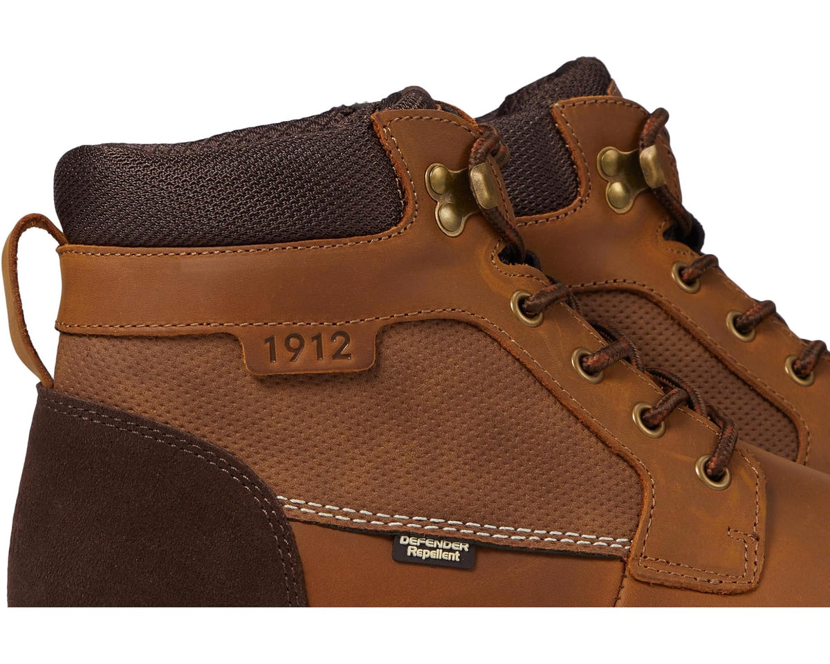 Close-up tan Nunn Bush chukka boots with 1912 patch, laces, and Defender Repellent label