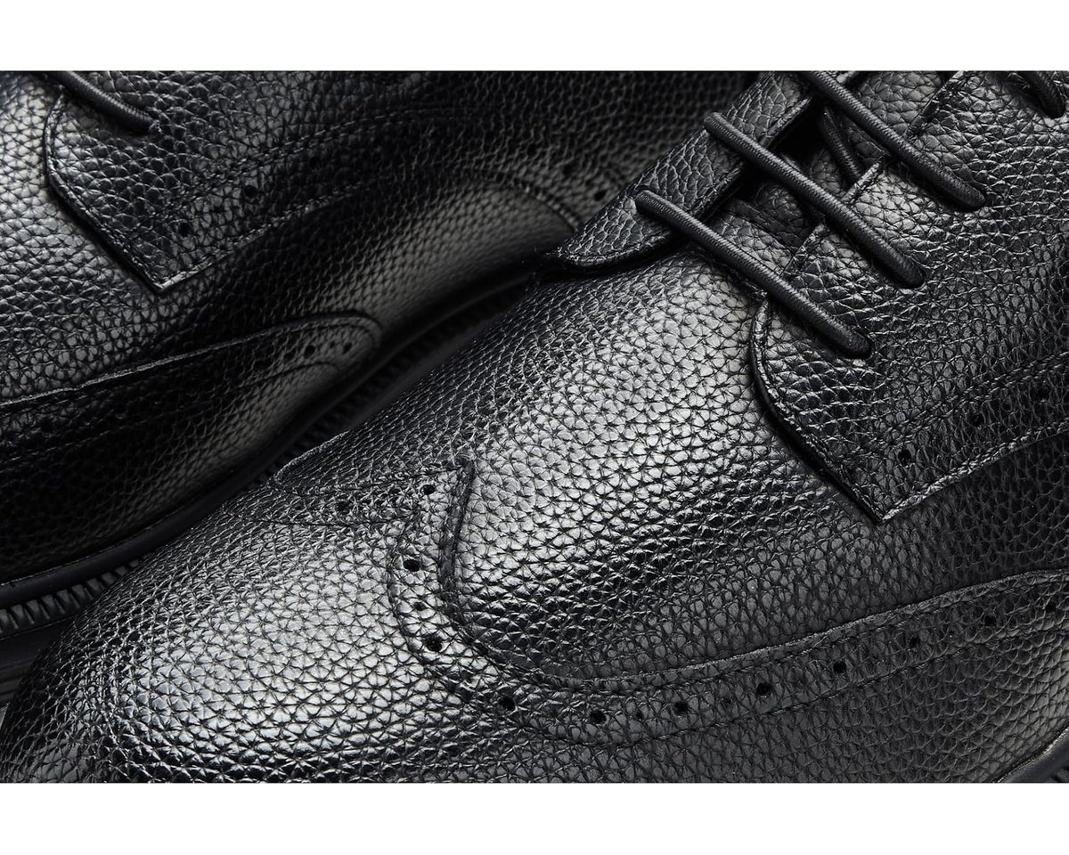 Black textured leather upper with lace eyelets and padded tongue on men's shoe