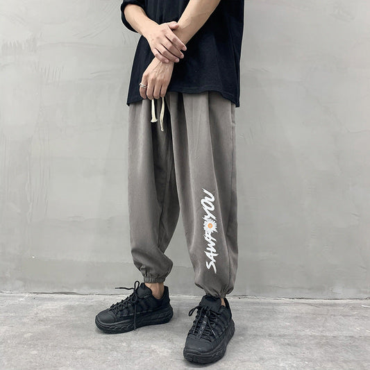 Grey jogger trousers with drawstring waist, relaxed tapered legs and side script print